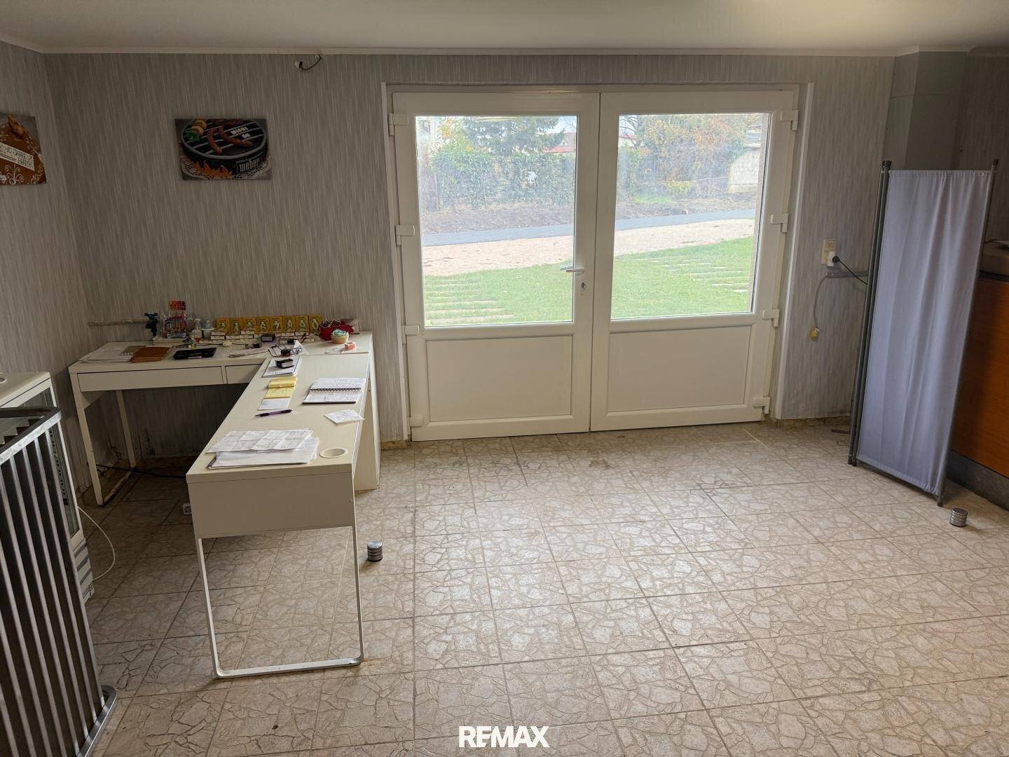 Arbeitszimmer oder Hobbyraum mit Schreibtisch und Zugang zum Garten durch eine Glastür.