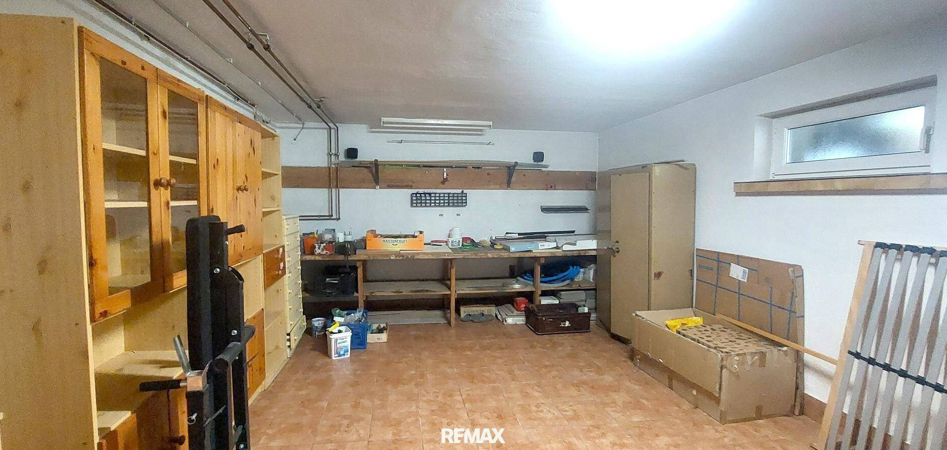 Geräumiger Hauswirtschaftsraum im Keller mit Fliesenboden, Holzregalen und einem kleinen Fenster.