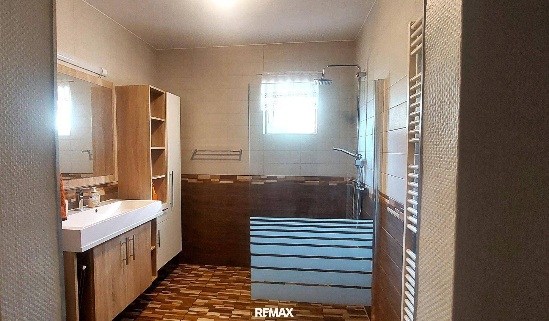 Modernes Badezimmer mit ebenerdiger Dusche, Einzelwaschbecken und beheiztem Handtuchhalter.