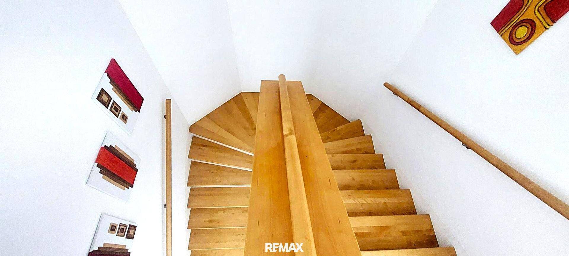 Elegante Holzwendeltreppe, die zu den oberen Etagen führt, mit heller Wandgestaltung.