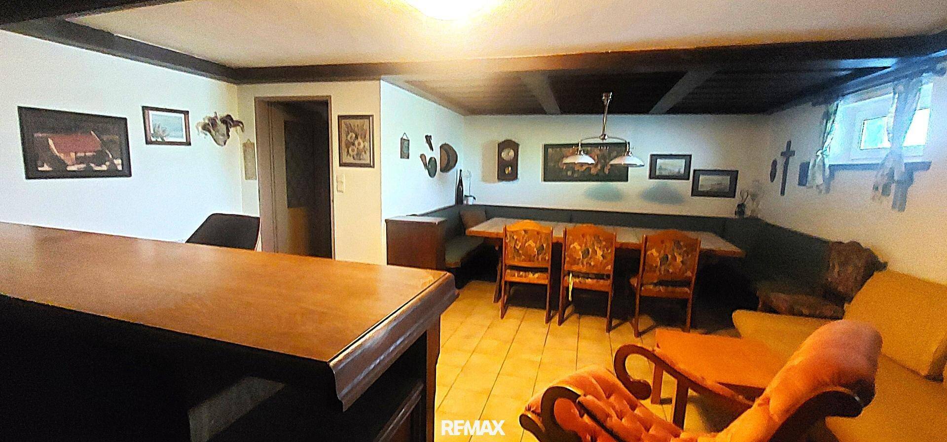Gemütlicher Wohn- und Freizeitbereich im Keller mit Bar, Esstisch und Holzbalkendecke.