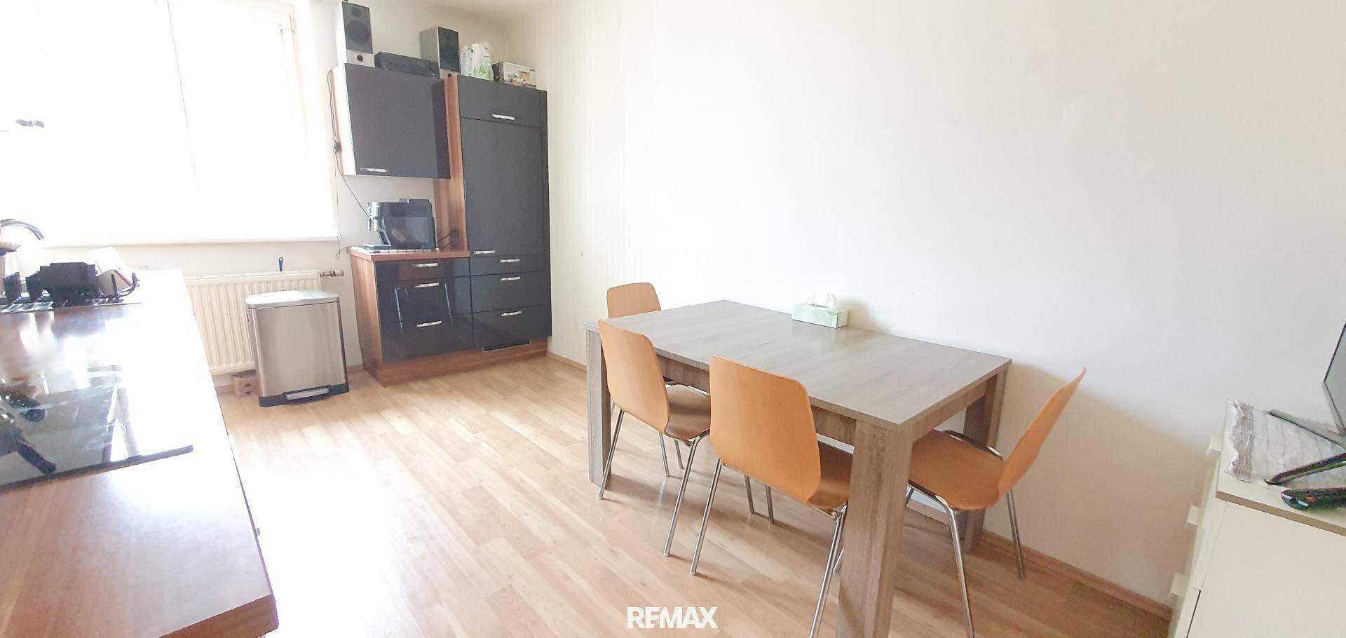 Funktionale Küche mit Essbereich, dunklen Schränken und hellem Laminatboden.