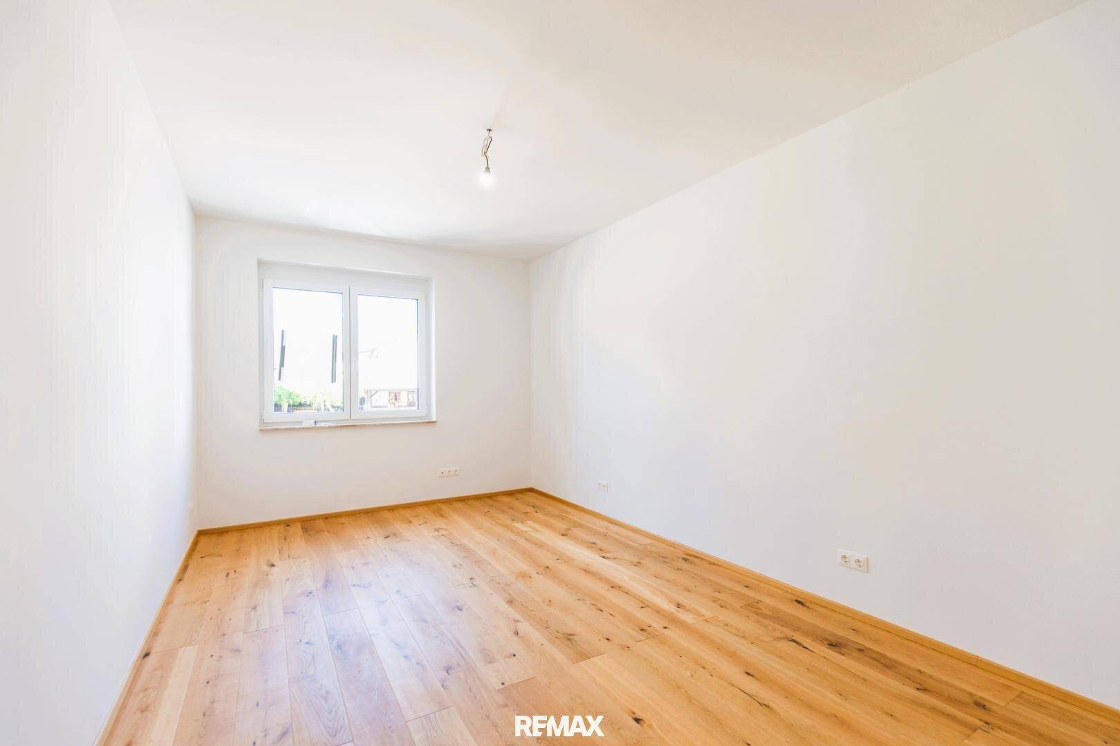 Ruhiges Schlafzimmer mit Holzboden und einem Fenster, das für natürliche Belichtung sorgt.