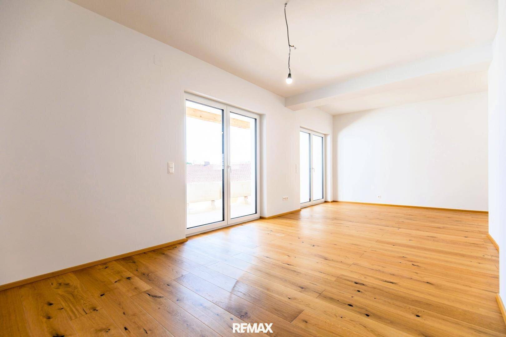 Lichtdurchfluteter Raum mit Holzboden und Zugang zu einem Balkon, ideal für einen Wohnbereich.