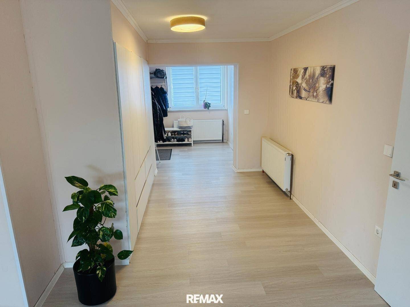 Heller Flur mit hellem Laminatboden, Einbauschränken und einer Zimmerpflanze.