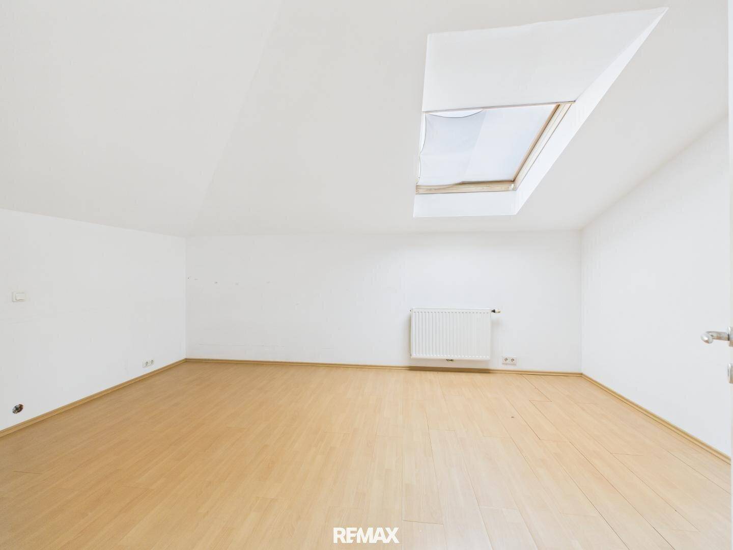 Heller Dachbodenraum mit Holzboden und einem Dachfenster, das für natürliches Licht sorgt.