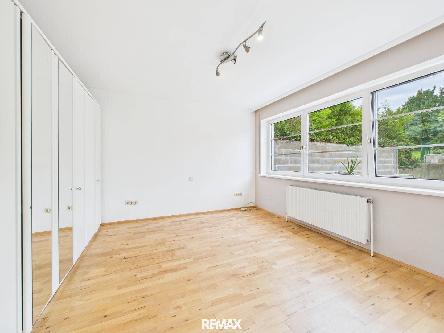 Schlafzimmer mit Holzboden, großen Fenstern und Einbauschränken, die viel Stauraum bieten.