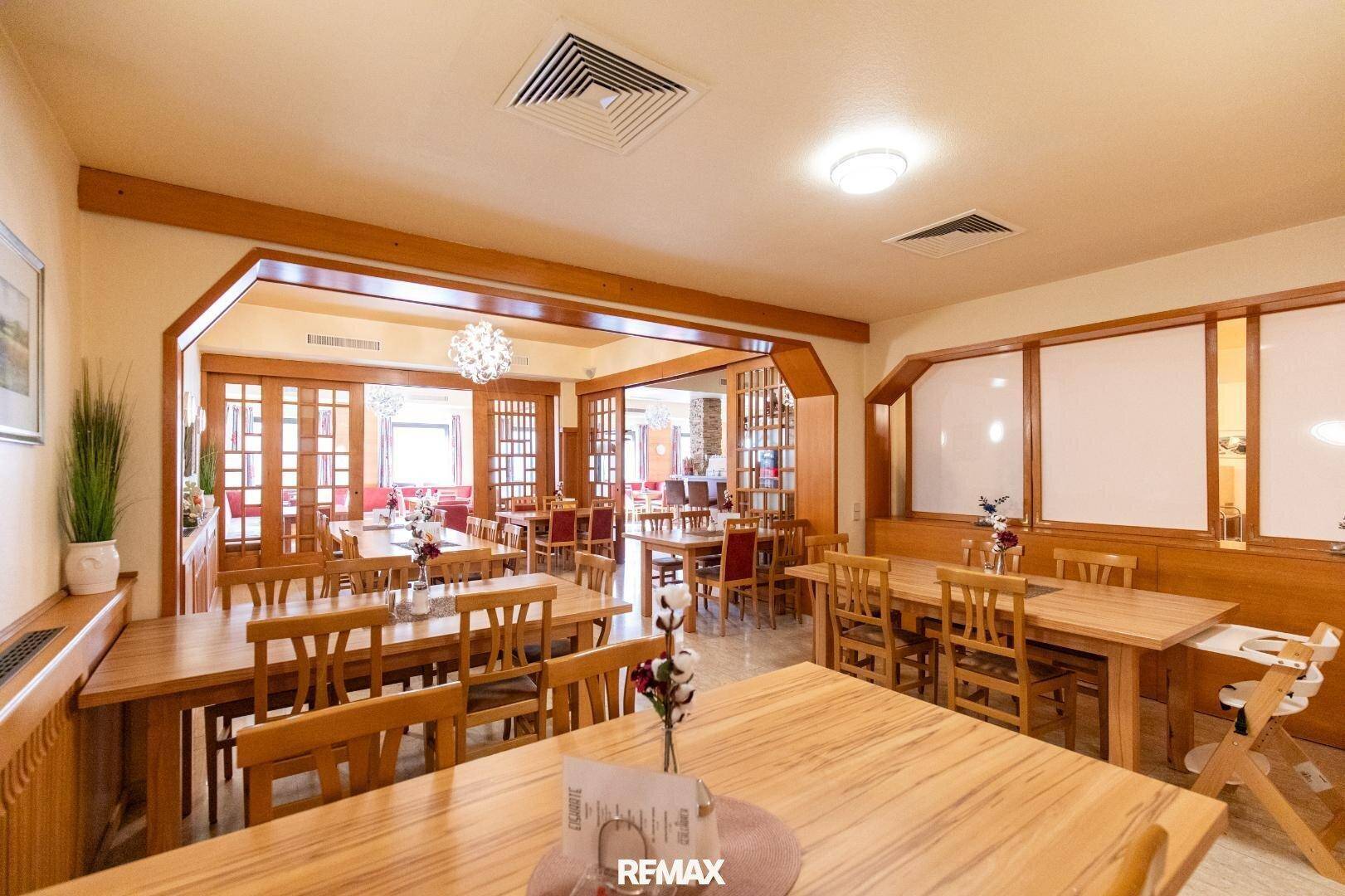 Großer Speisesaal mit vielen Holztischen und Stühlen, getrennt durch Holzelemente.