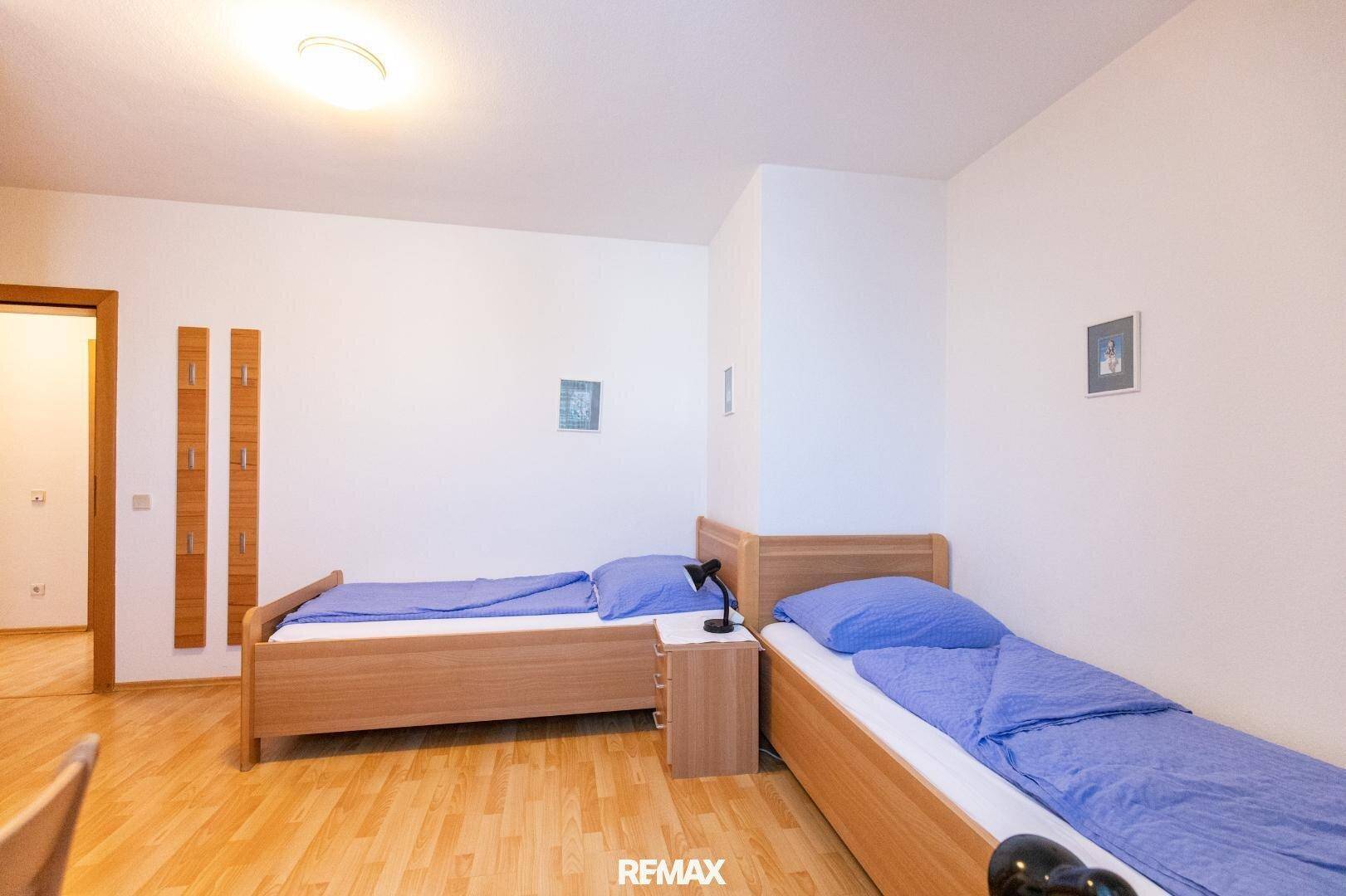 Schlafzimmer mit zwei Einzelbetten, Holzboden und schlichter Einrichtung, ideal für Gäste.