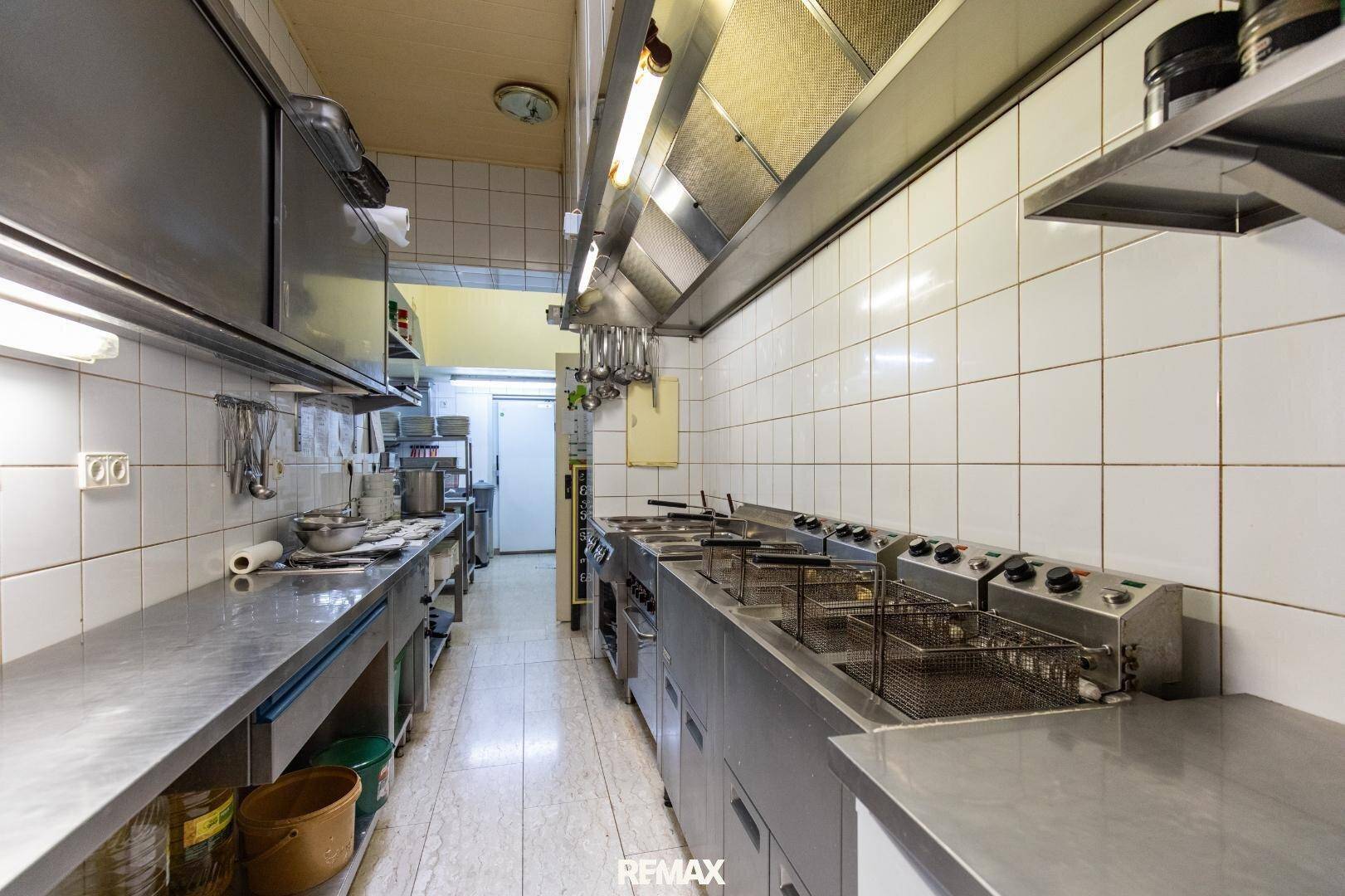 Lange Reihe von Edelstahl-Arbeitsflächen und Fritteusen in einer professionellen Restaurantküche.