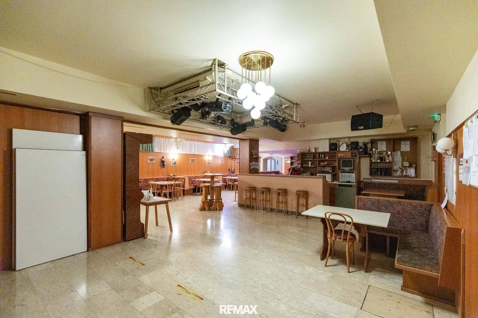 Großer Bar- und Loungebereich mit Marmorboden, Sitzgelegenheiten und einer Bühne mit Beleuchtung.