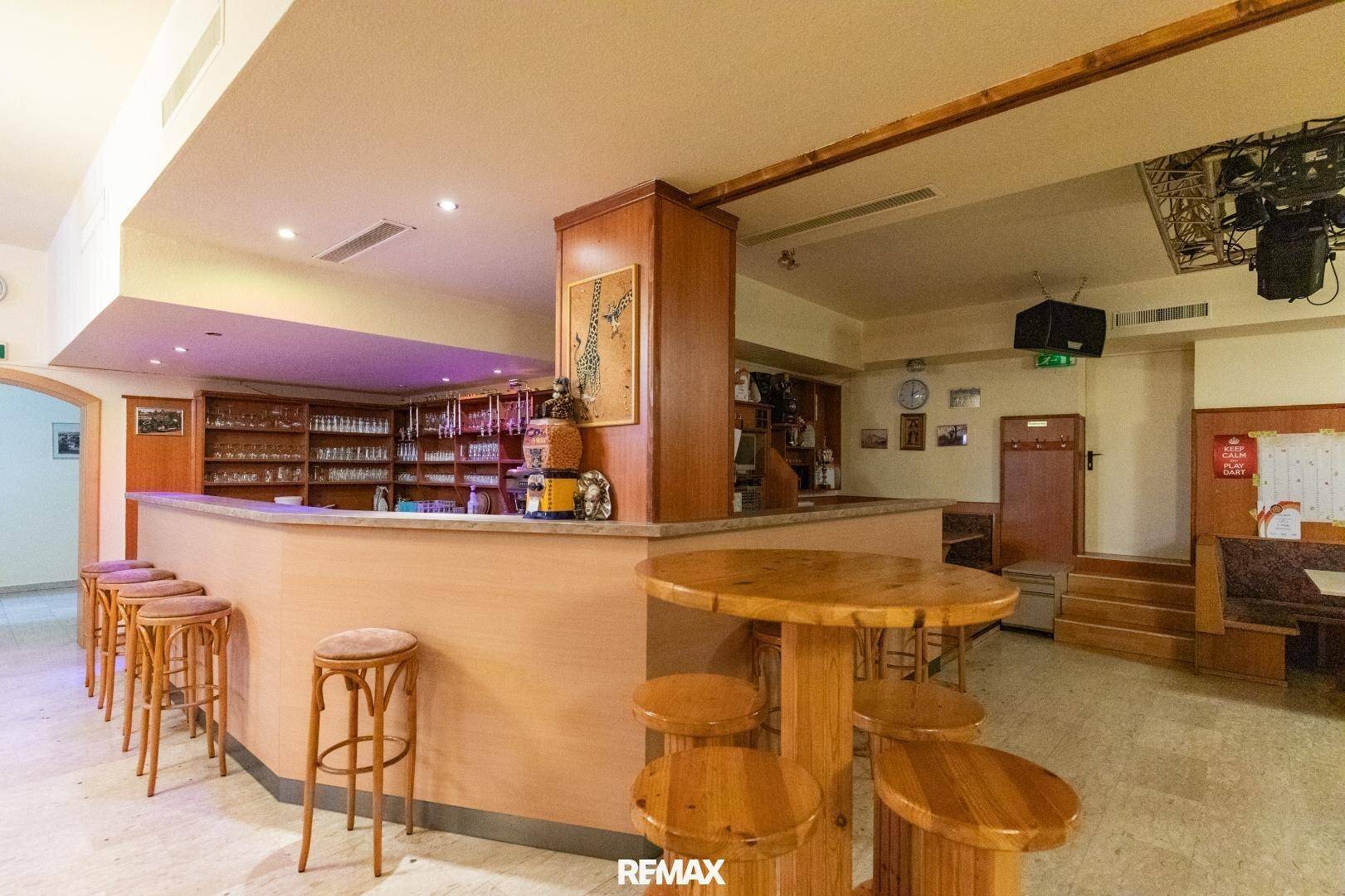 Thekenbereich mit Holzmöbeln, Barhockern und einer gut ausgestatteten Bar mit Getränken.