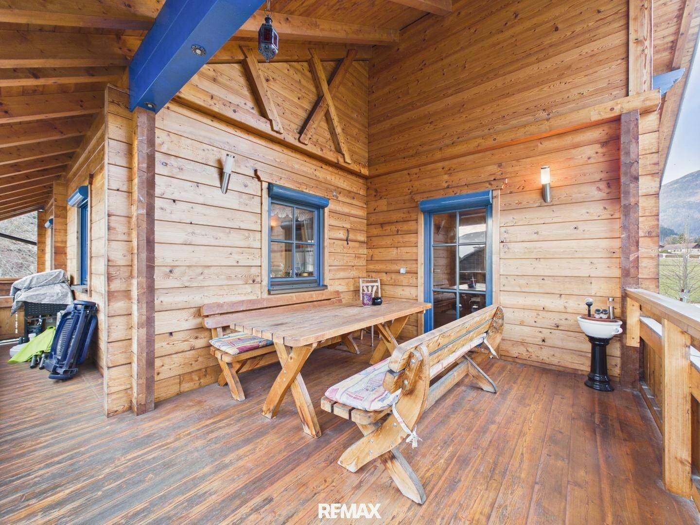 Großer Holzbalkon mit Sitzgelegenheiten und Bergblick, ideal für Mahlzeiten im Freien.