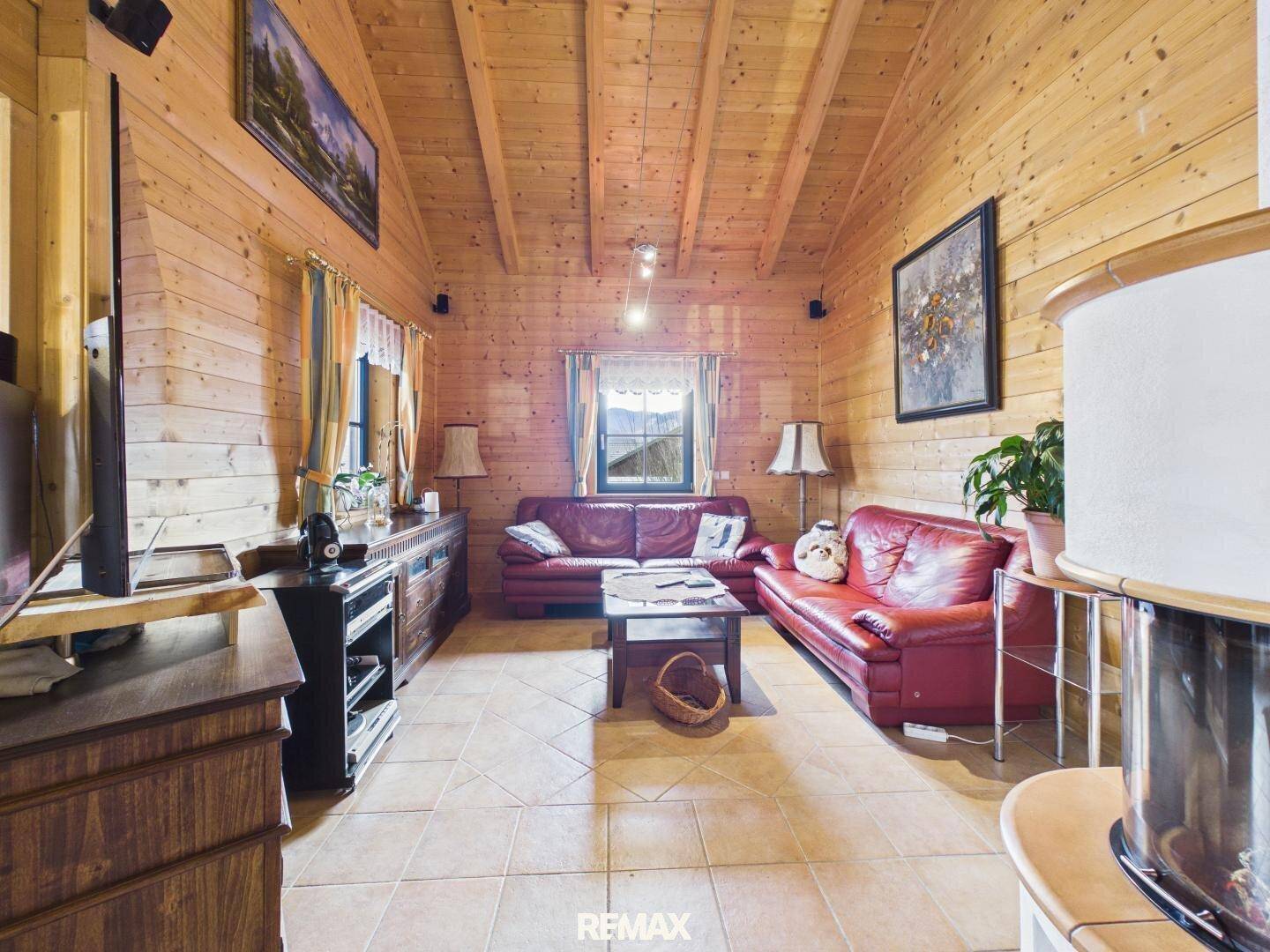 Rustikales Wohnzimmer mit Holzwänden, Holzbalkendecke und gemütlichen Ledersofas.