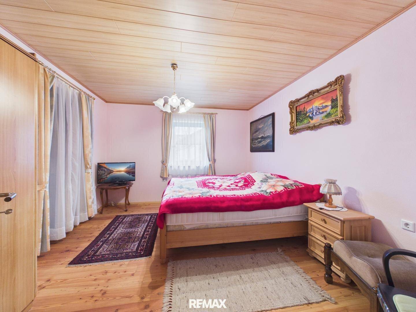 Helles Schlafzimmer mit Holzboden, rosa Wänden und traditioneller Einrichtung.