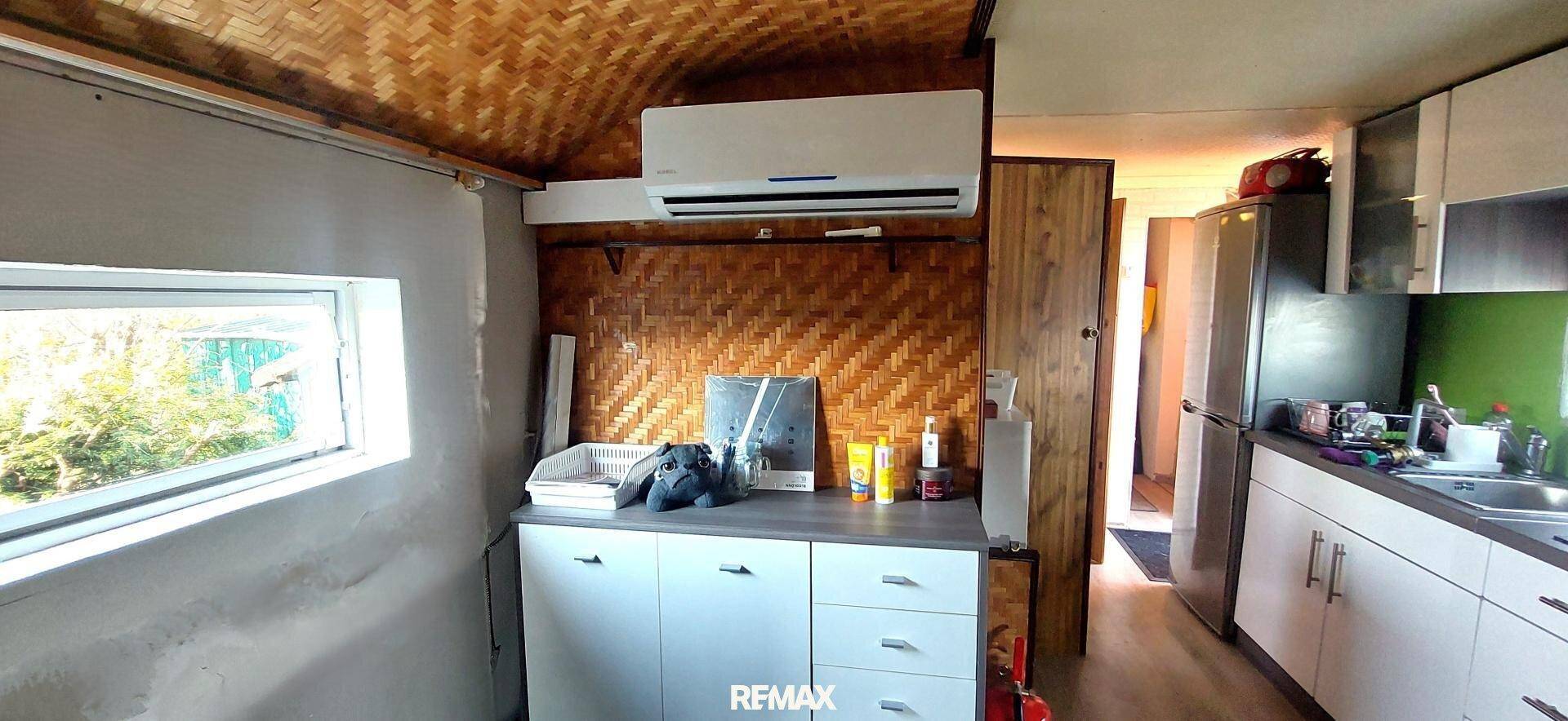 Küchenbereich mit Klimaanlage, geflochtener Decke und einem Fenster mit Blick ins Grüne.