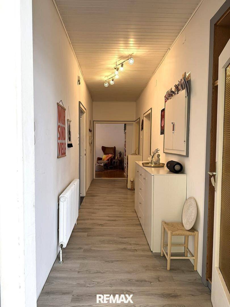Langer Flur mit Laminatboden, Kommode und Zugang zu weiteren Räumen.
