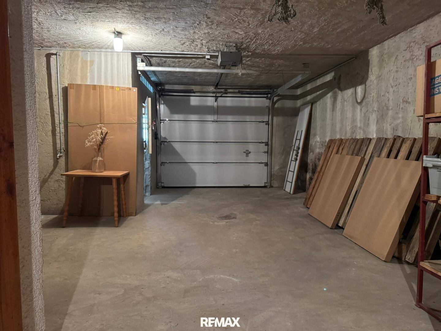 Geräumige Garage im Untergeschoss mit Betonboden und großem Garagentor.
