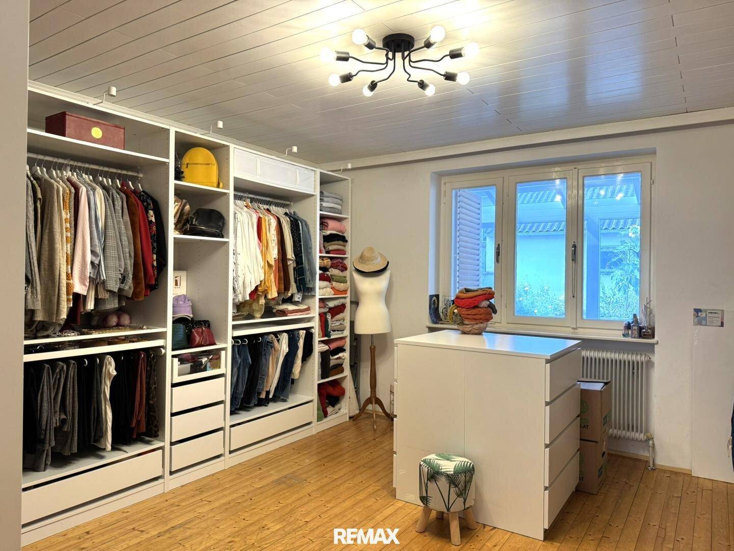 Geräumiges Ankleidezimmer mit offenen Schränken, viel Stauraum und Holzboden.