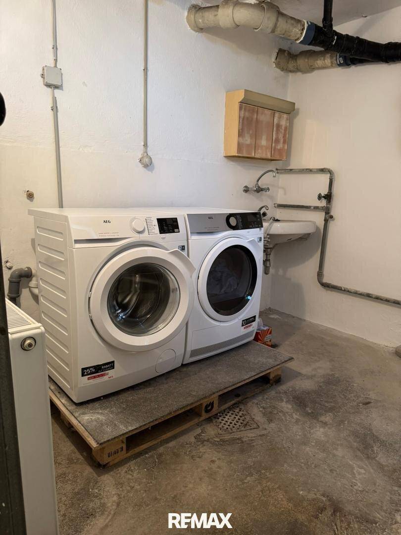 Waschküche im Keller mit Waschmaschine, Trockner und Waschbecken.