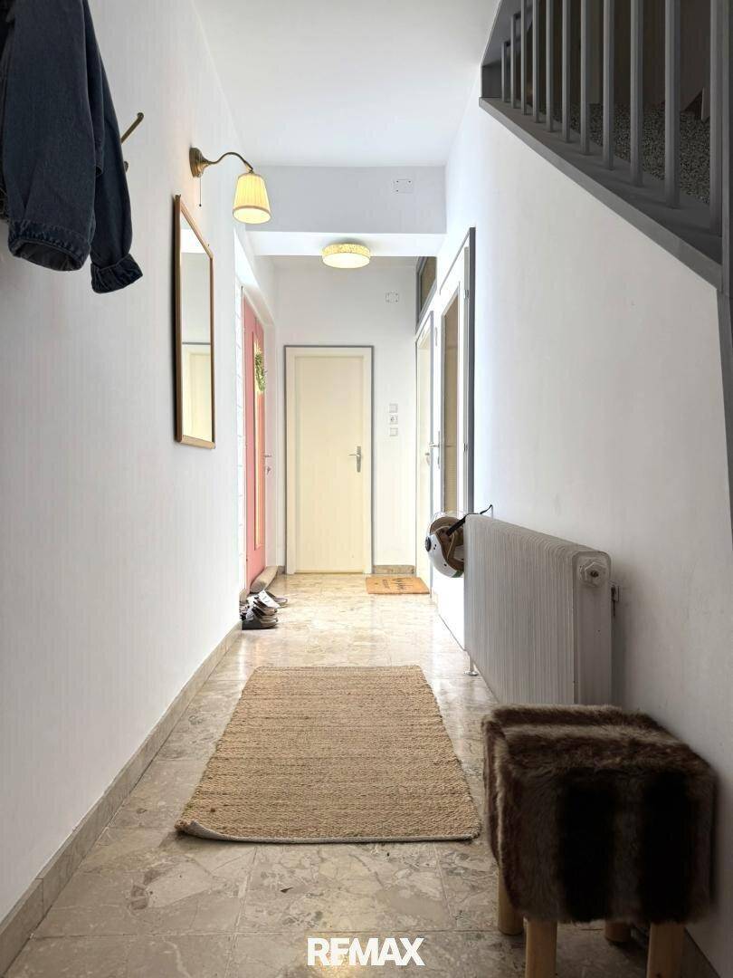 Heller Flur mit Fliesenboden, Garderobe und Treppenaufgang zum Obergeschoss.
