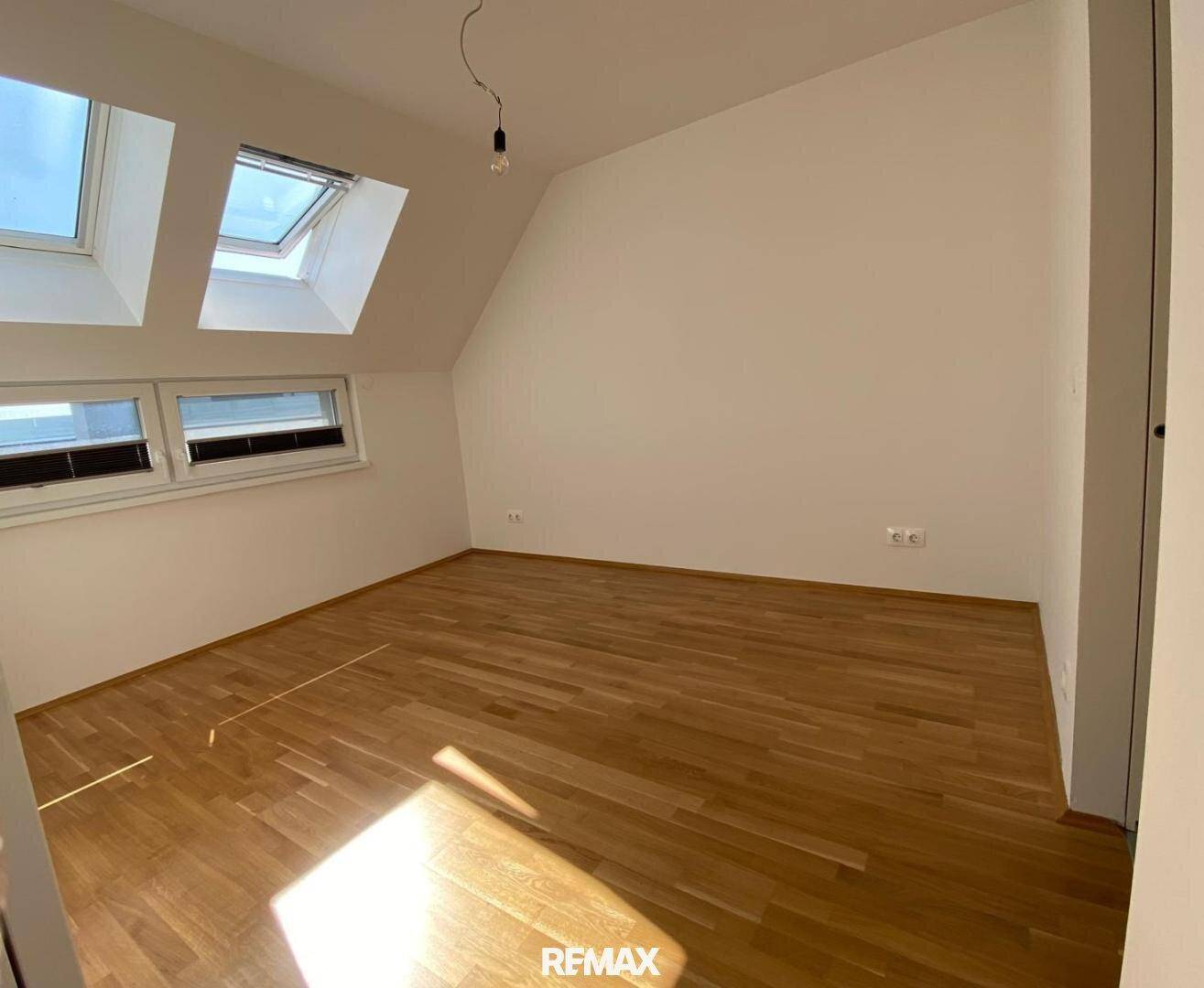 Helles Zimmer mit Dachschrägen, Parkettboden und Dachfenstern für viel Tageslicht.