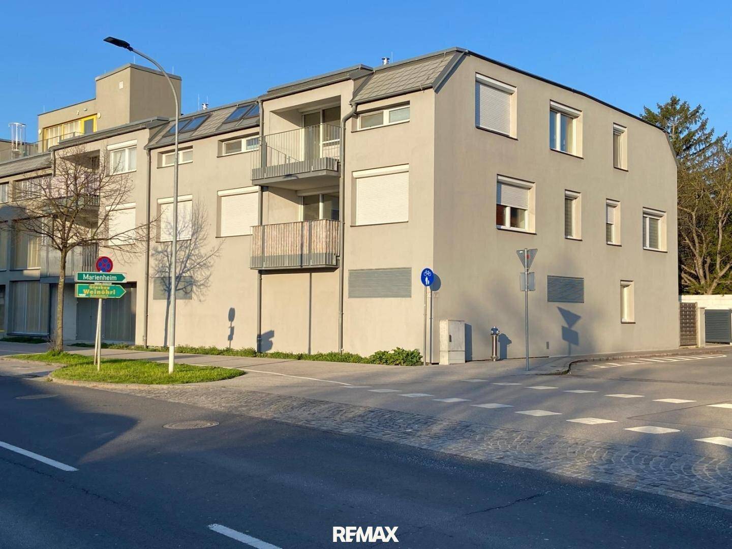 Modernes Mehrfamilienhaus mit mehreren Balkonen und großen Fenstern an einer Straßenecke.
