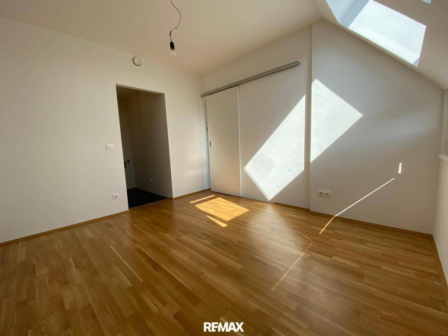 Geräumiges Zimmer mit Holzboden, Dachschrägen und viel natürlichem Lichteinfall.