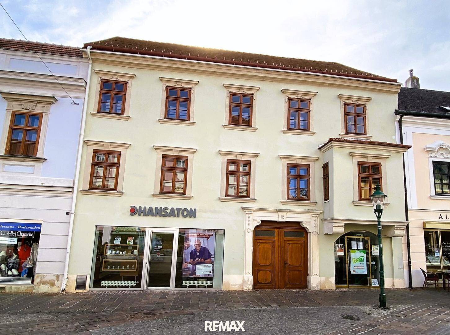 Historisches Gebäude mit traditioneller Fassade und Holztüren in einer belebten Stadtstraße.