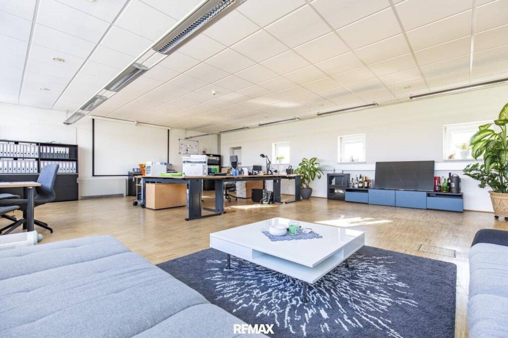 Großes, offenes Büro mit mehreren Arbeitsplätzen, einem Sofa und einem Couchtisch.