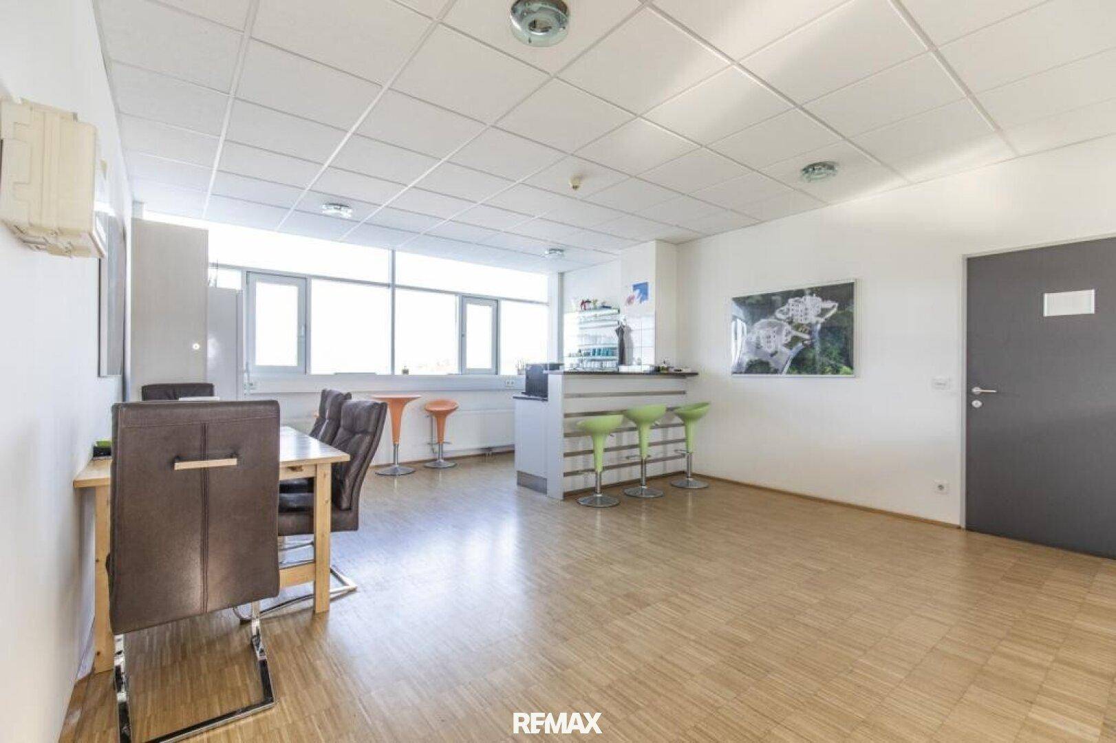 Heller Aufenthaltsraum mit einer kleinen Bar, Tischen und Stühlen, ideal für Pausen.