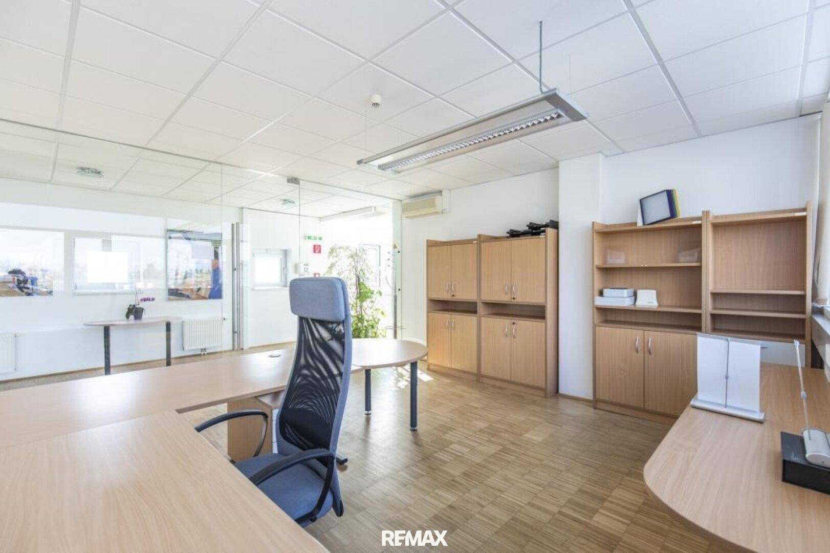 Helles Büro mit Schreibtischen, Bürostühlen und Holzschränken, gut beleuchtet.