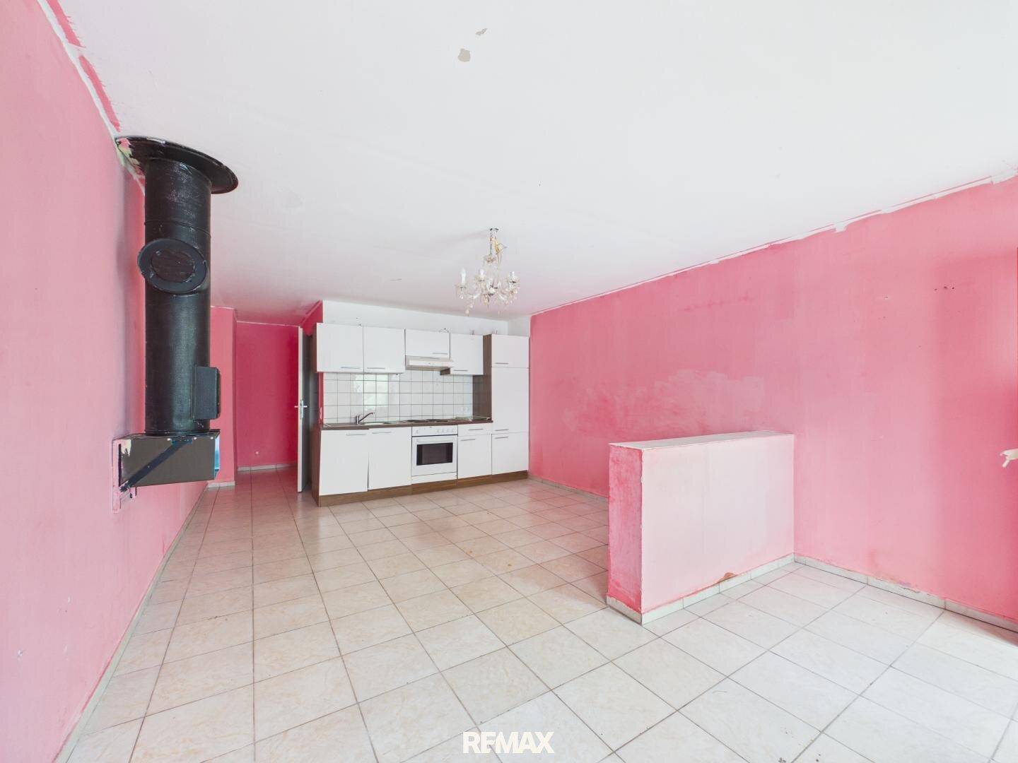 Küche mit rosa Wänden, Fliesenboden und einer einfachen weißen Küchenzeile mit Ofen.