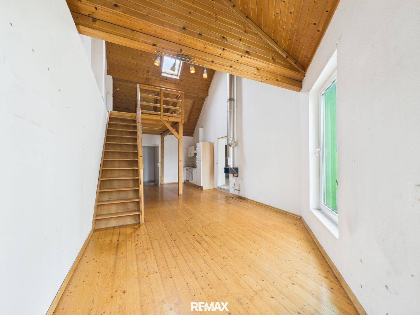 Offener Wohnbereich mit hohen Holzdecken, Holzboden und einer Galerie mit Treppenzugang.