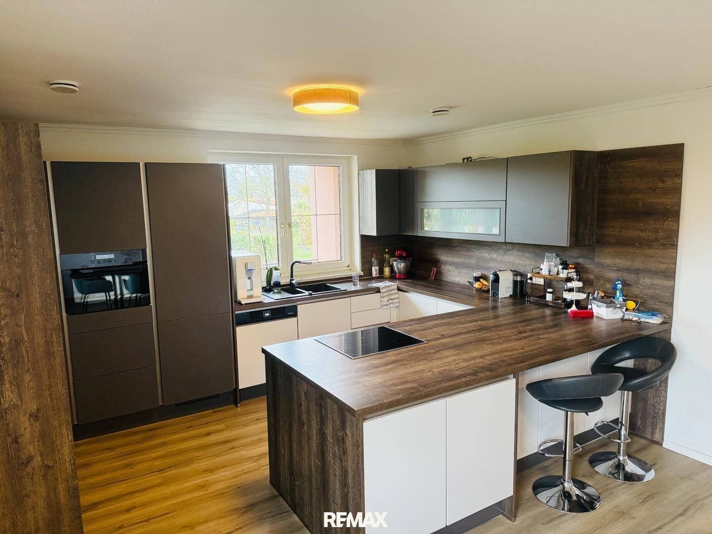 Moderne Küche mit Holz- und Weißtönen, Kochinsel und integrierten Geräten.