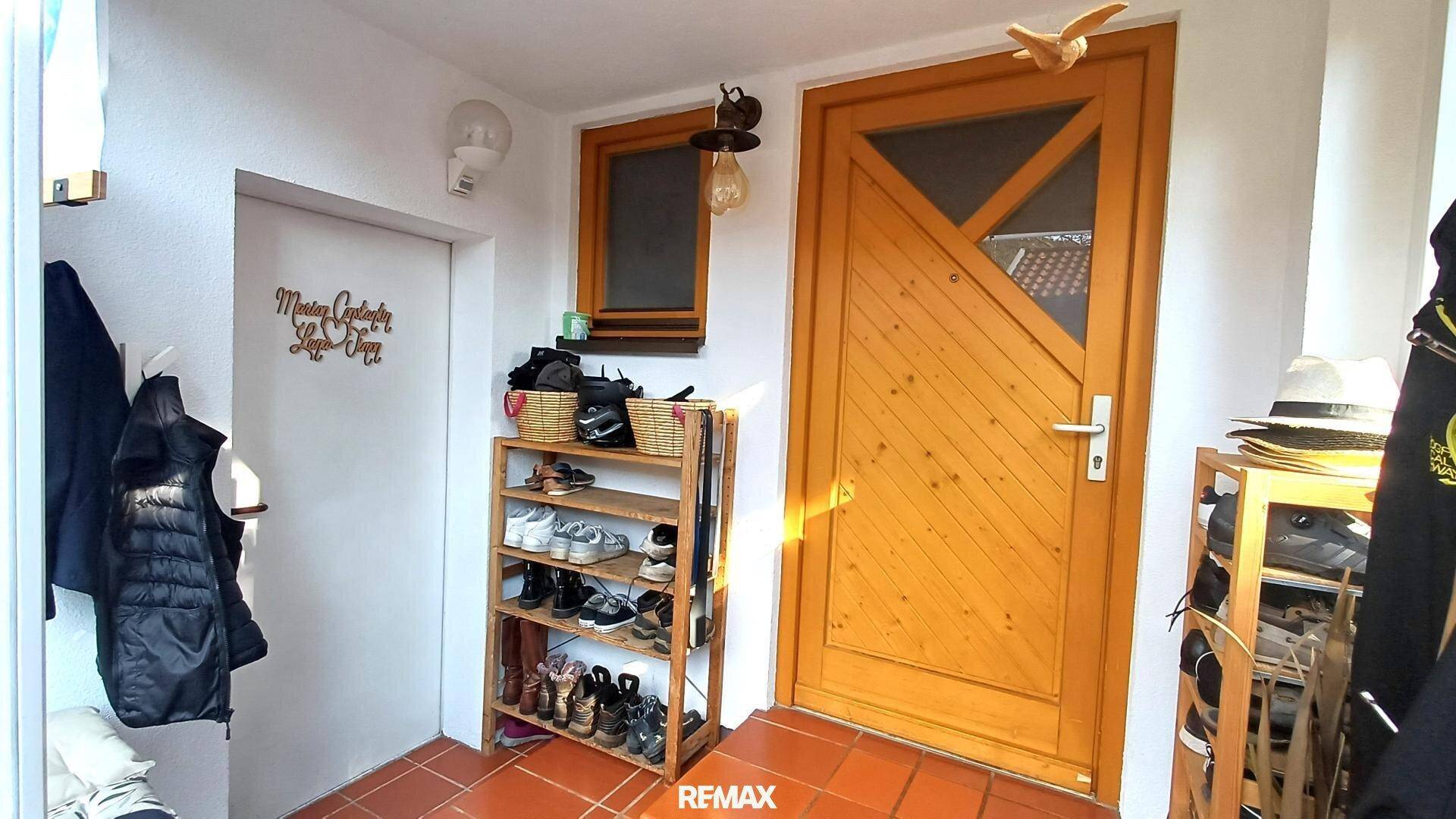 Eingangsbereich mit Holzhaustür, praktischem Schuhregal und Garderobe für Jacken und Hüte.