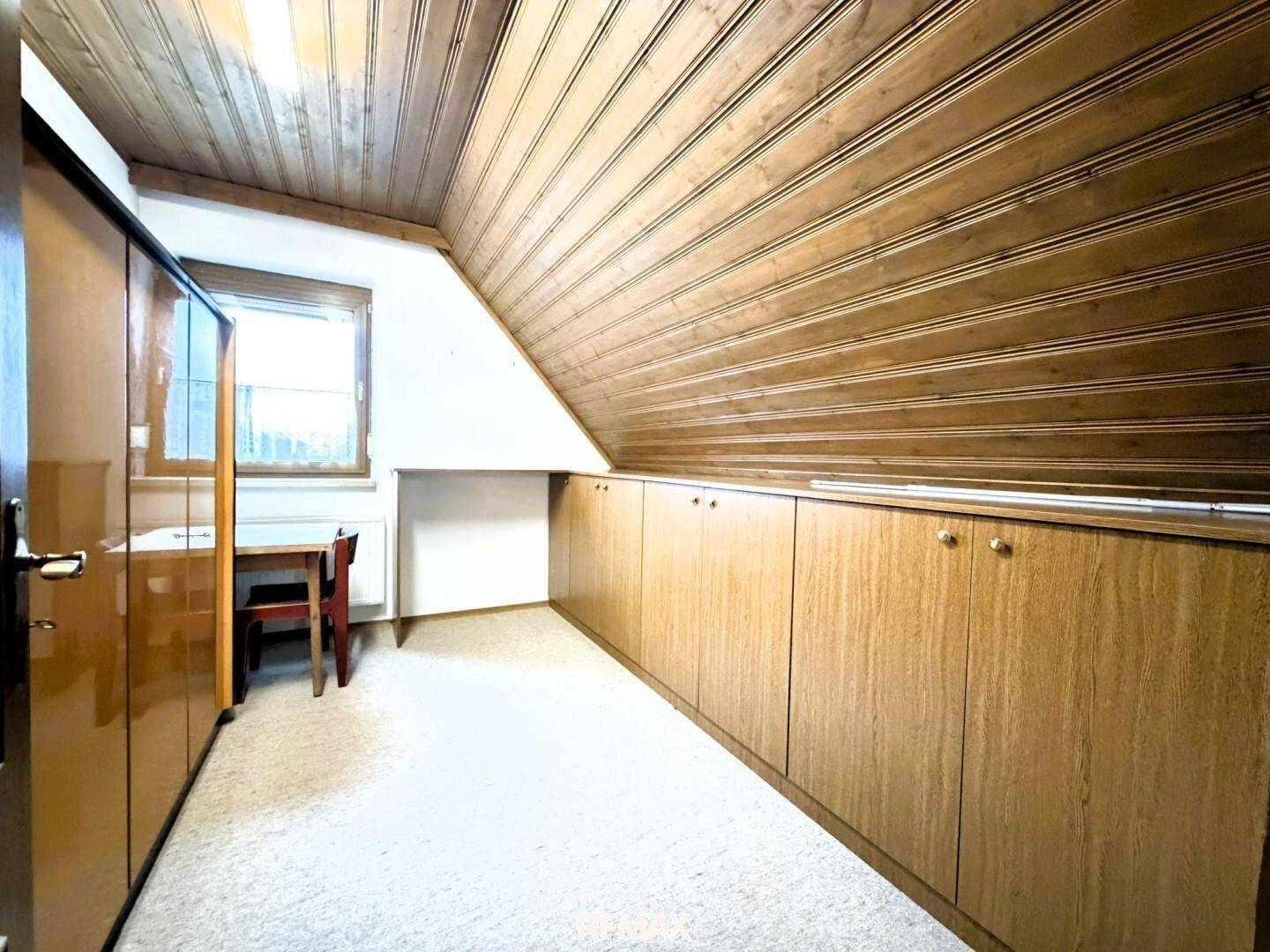 Abstellraum im Dachgeschoss mit Holzdecke, Teppichboden und Einbauschränken.