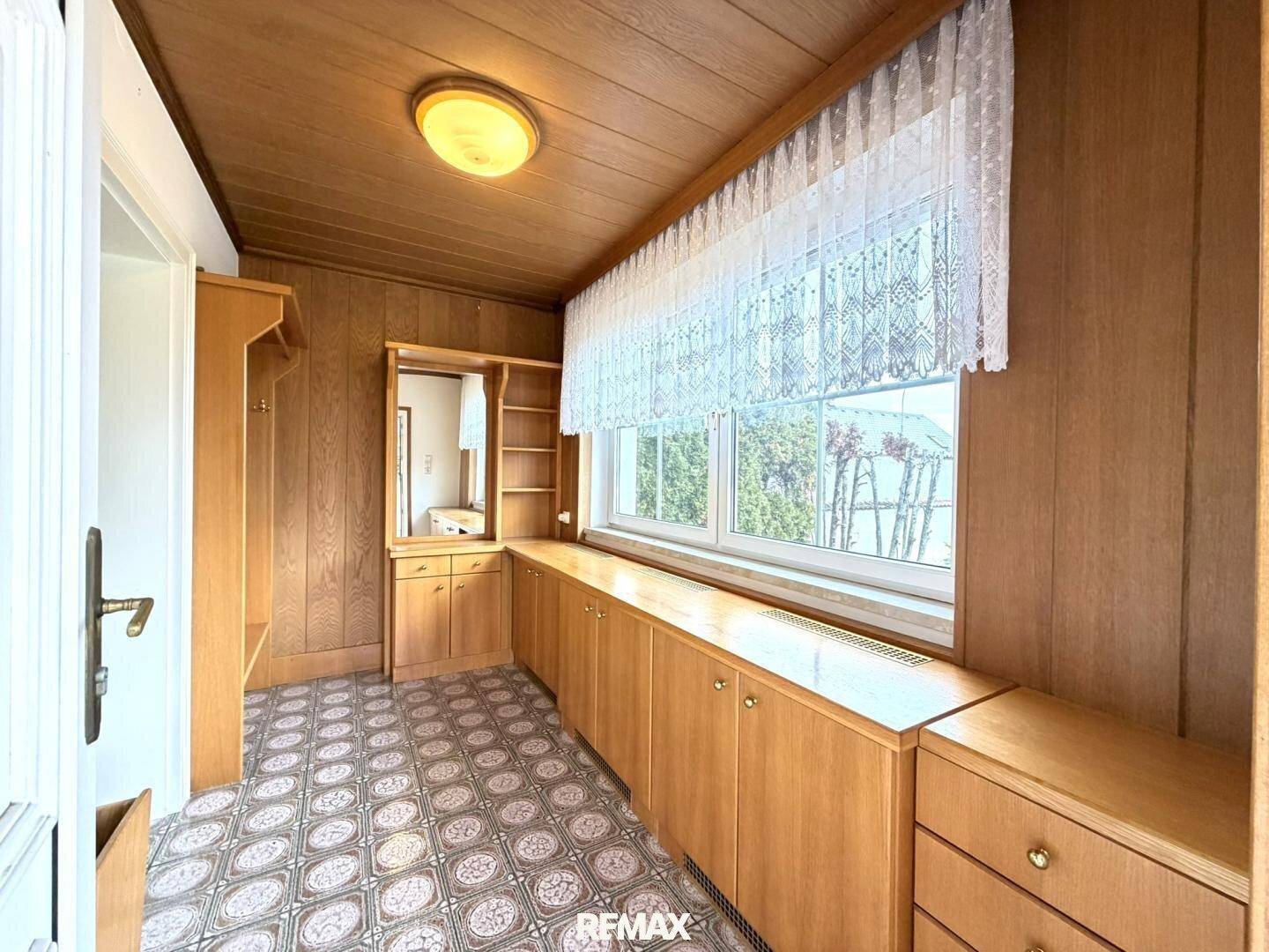 Gemütlicher Eingangsbereich mit Holzvertäfelung, Einbauschränken und Fenster.