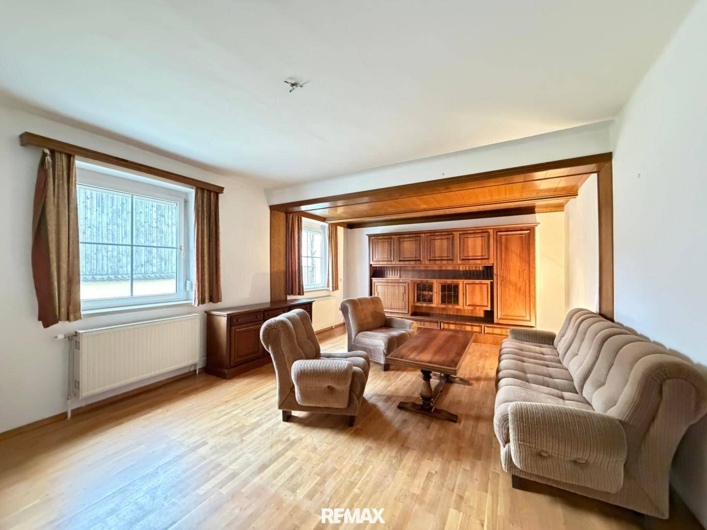 Geräumiges Wohnzimmer mit Holzbalken, Parkettboden und traditionellen Möbeln.