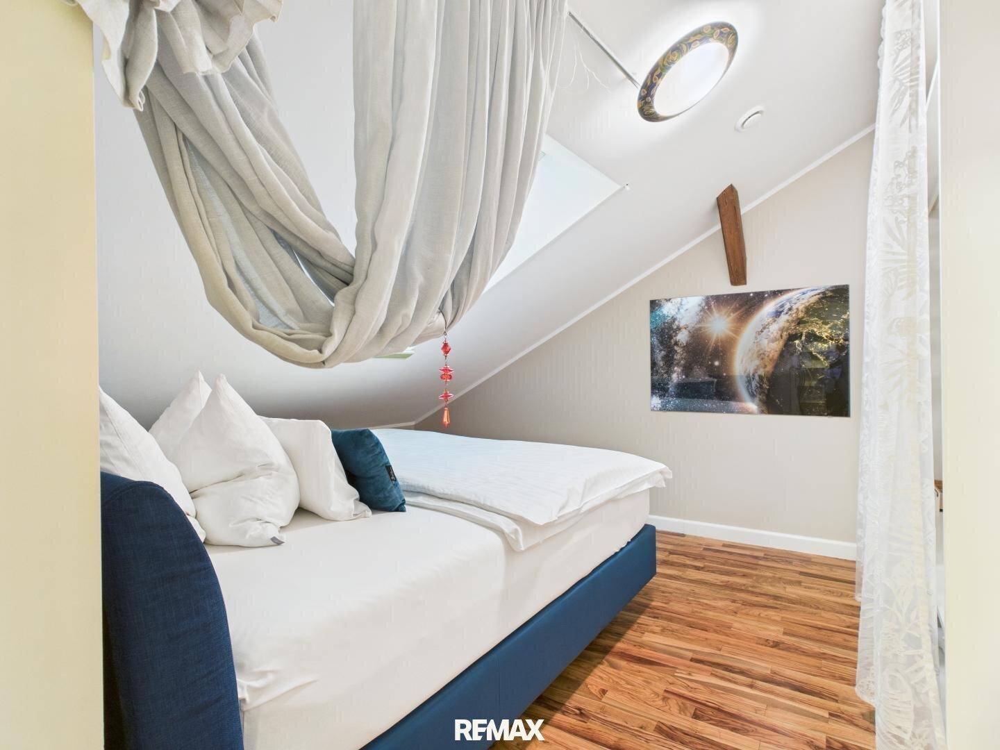 Helles Schlafzimmer im Dachgeschoss mit Dachschräge, Dachfenster und bequemen Bett.
