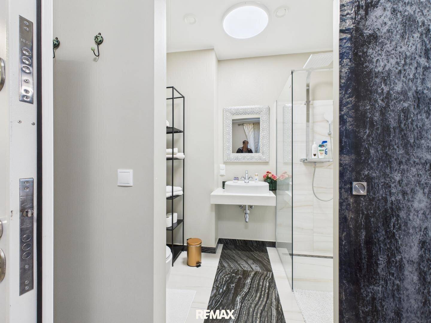 Modernes Badezimmer mit begehbarer Dusche, Einzelwaschbecken und stilvollem Spiegel.