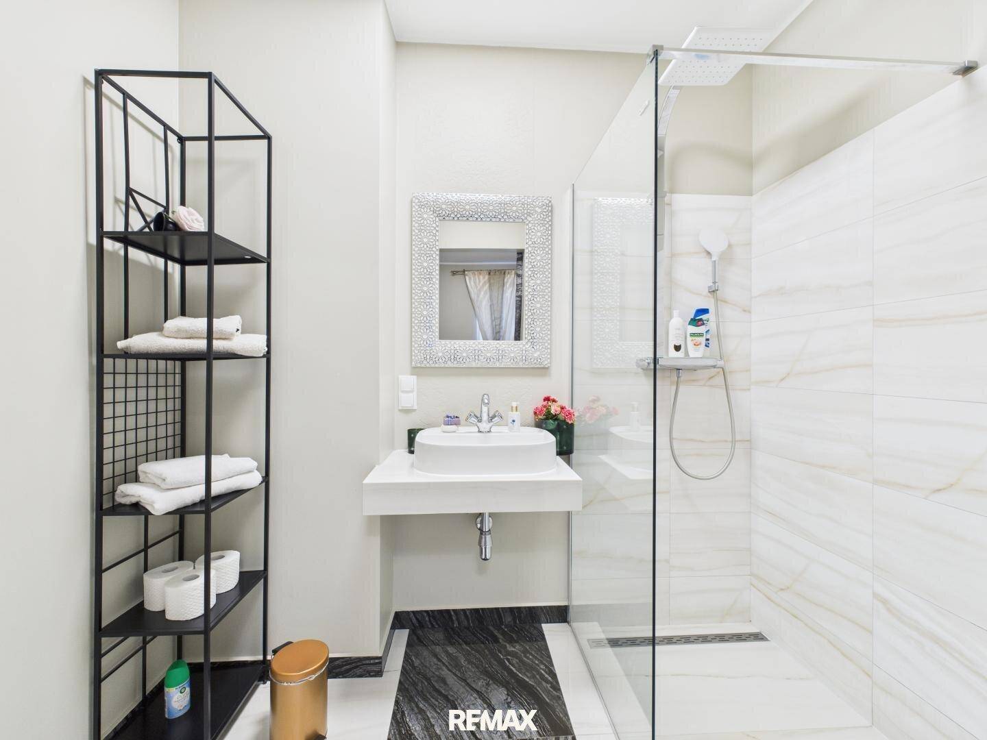 Detailansicht des modernen Badezimmers mit elegantem Waschbecken und großer Duschkabine.