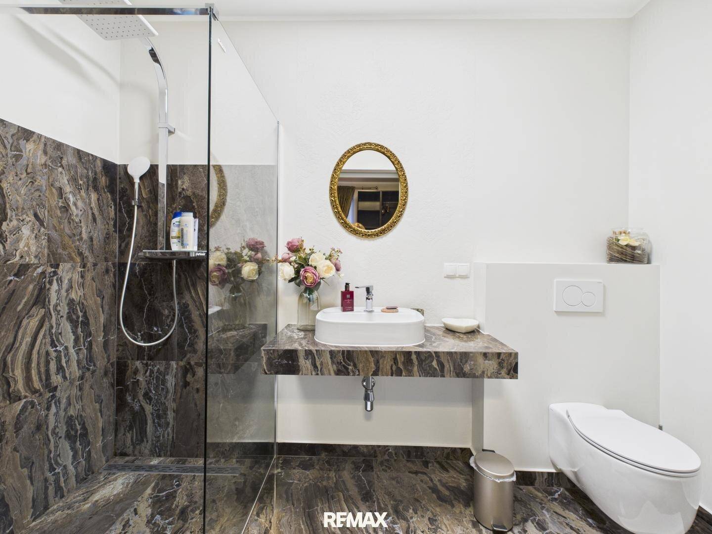 Elegantes Badezimmer mit begehbarer Dusche, wandhängendem WC und Marmoroberflächen.