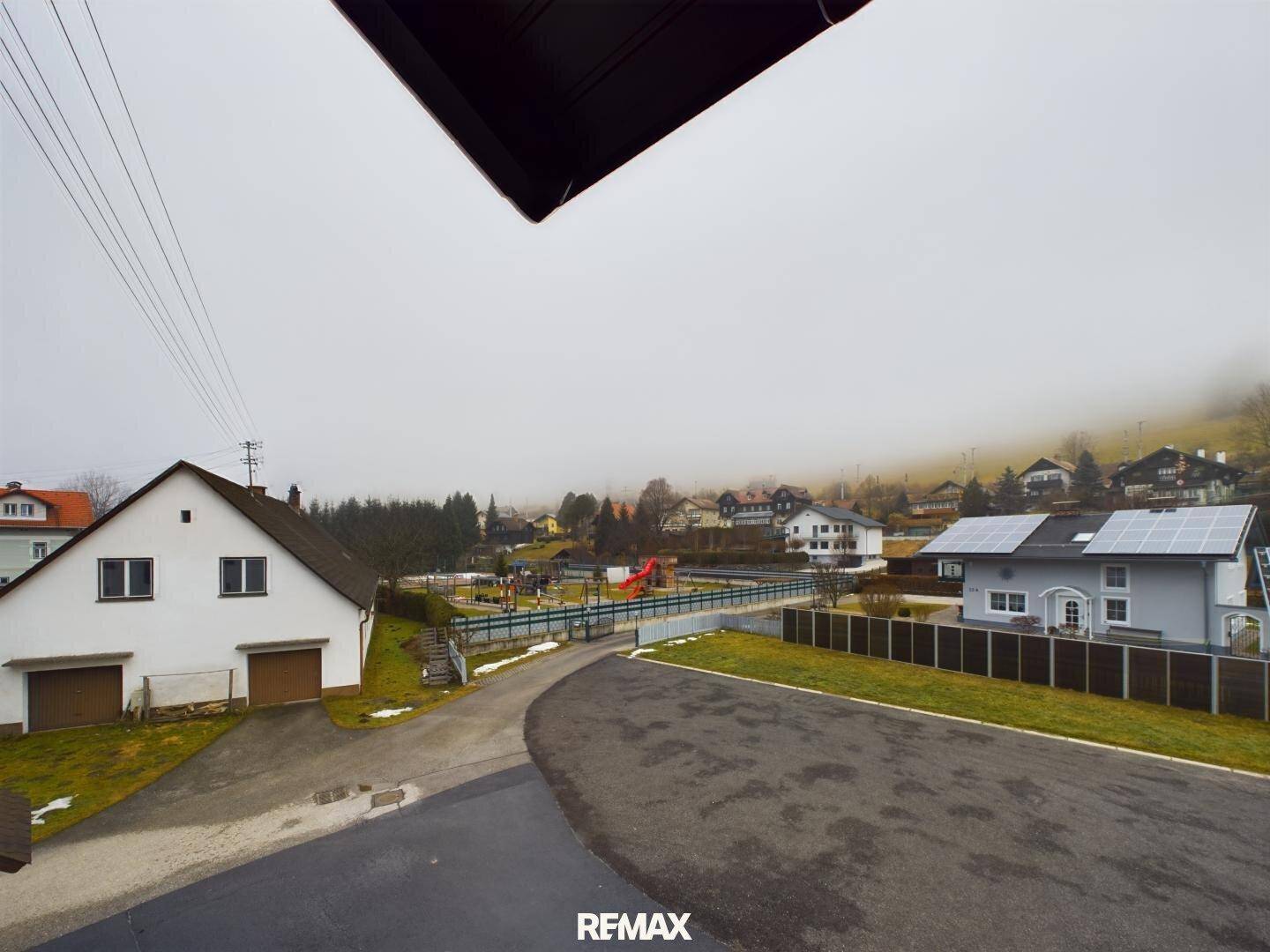 Weitläufiger Blick auf eine ländliche Umgebung mit Häusern, Spielplatz und Solaranlagen.