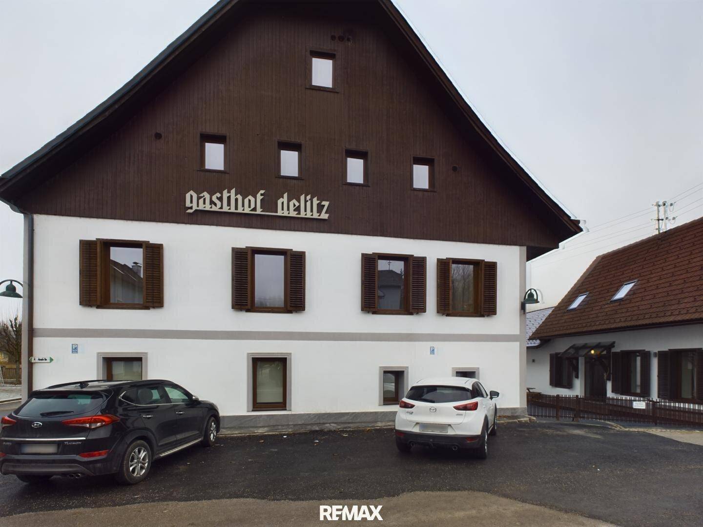 Nahaufnahme der Fassade des Gasthofs Delitz mit traditionellen Fensterläden und Parkmöglichkeiten.