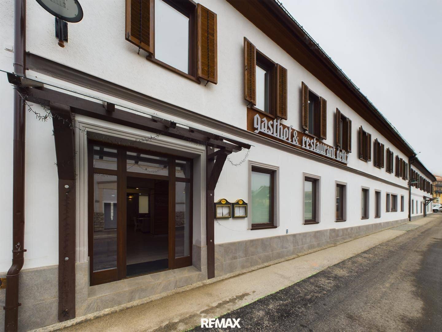 Fassade eines Gasthofs mit traditionellen Holzfensterläden und einem Eingangsbereich.