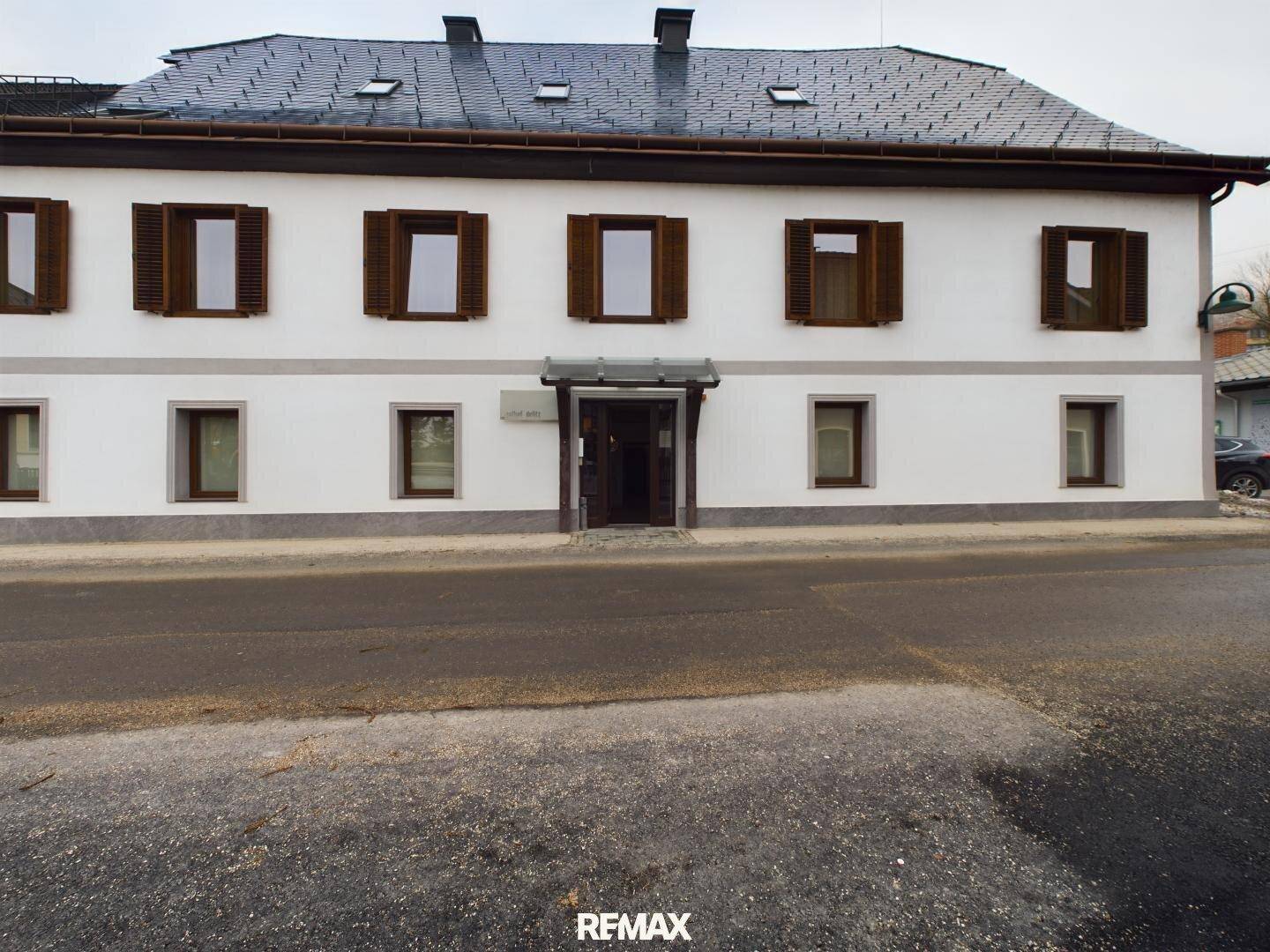 Gasthofgebäude mit weißer Fassade, braunen Fensterläden und einem Schieferdach.