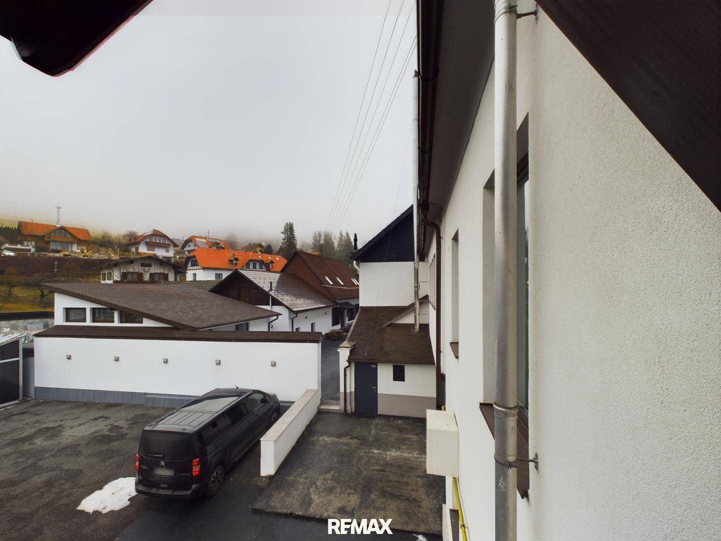 Blick von oben auf einen Parkplatz mit einem schwarzen Van und umliegenden Häusern.