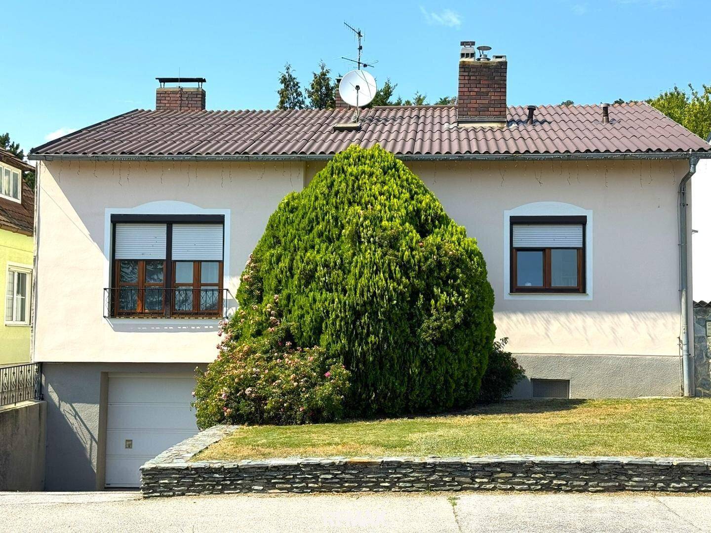 Vorderansicht des Hauses mit integrierter Garage und gepflegtem Vorgarten.