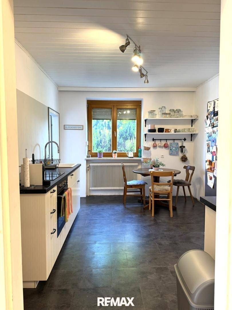 Funktionale Küche mit Essbereich, dunklem Boden und Fenster.